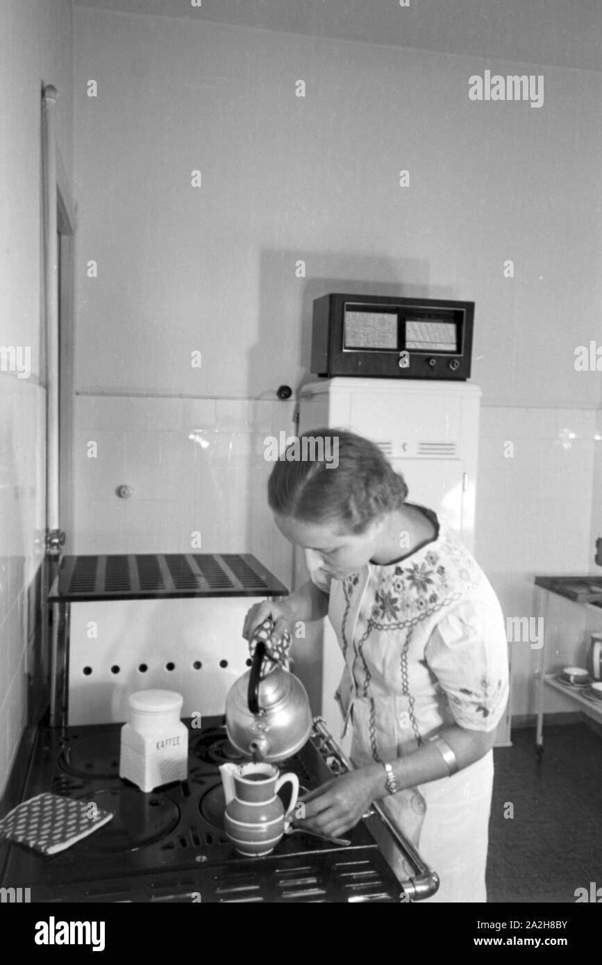 Eine Frau brüht Kaffee in der Küche auf und hört dabei Radio, Deutschland 1930er Jahre. A woman preparing coffee while listening to the radio, Germany 1930s. Stock Photo