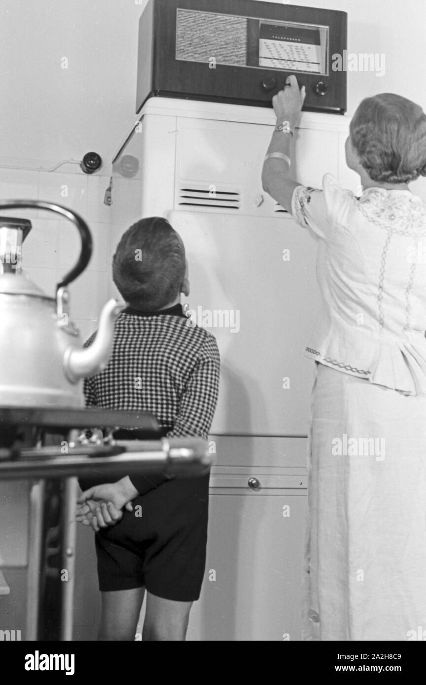 Mutter und Sohn hören Radio in der Küche, Deutschland 1930er Jahre. Mother and son listening to the radio at the kitchen, Germany 1930s. Stock Photo