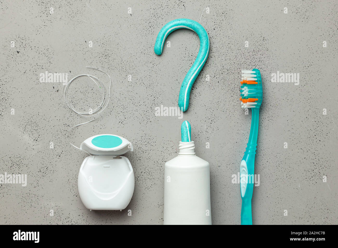 Toothpaste in the form of a question mark and toothbrushes and dental floss. Concept of how to