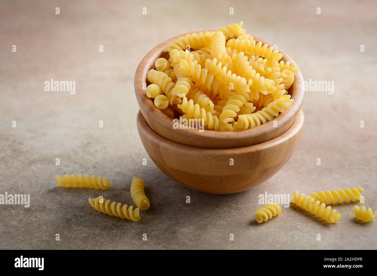 Raw fusilli pasta in a wooden bowl. Stock Photo