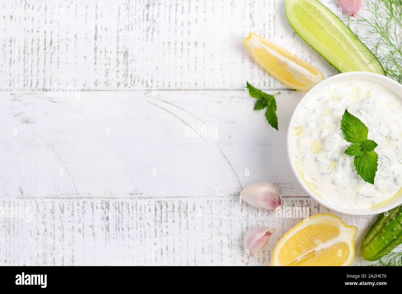 Greek dip sauce or dressing tzatziki decorated with olive oil and mint on white wooden table Stock Photo