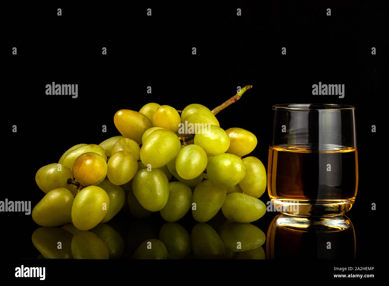 Two glasses of white wine and a bunch of grapes isolated on black Stock Photo