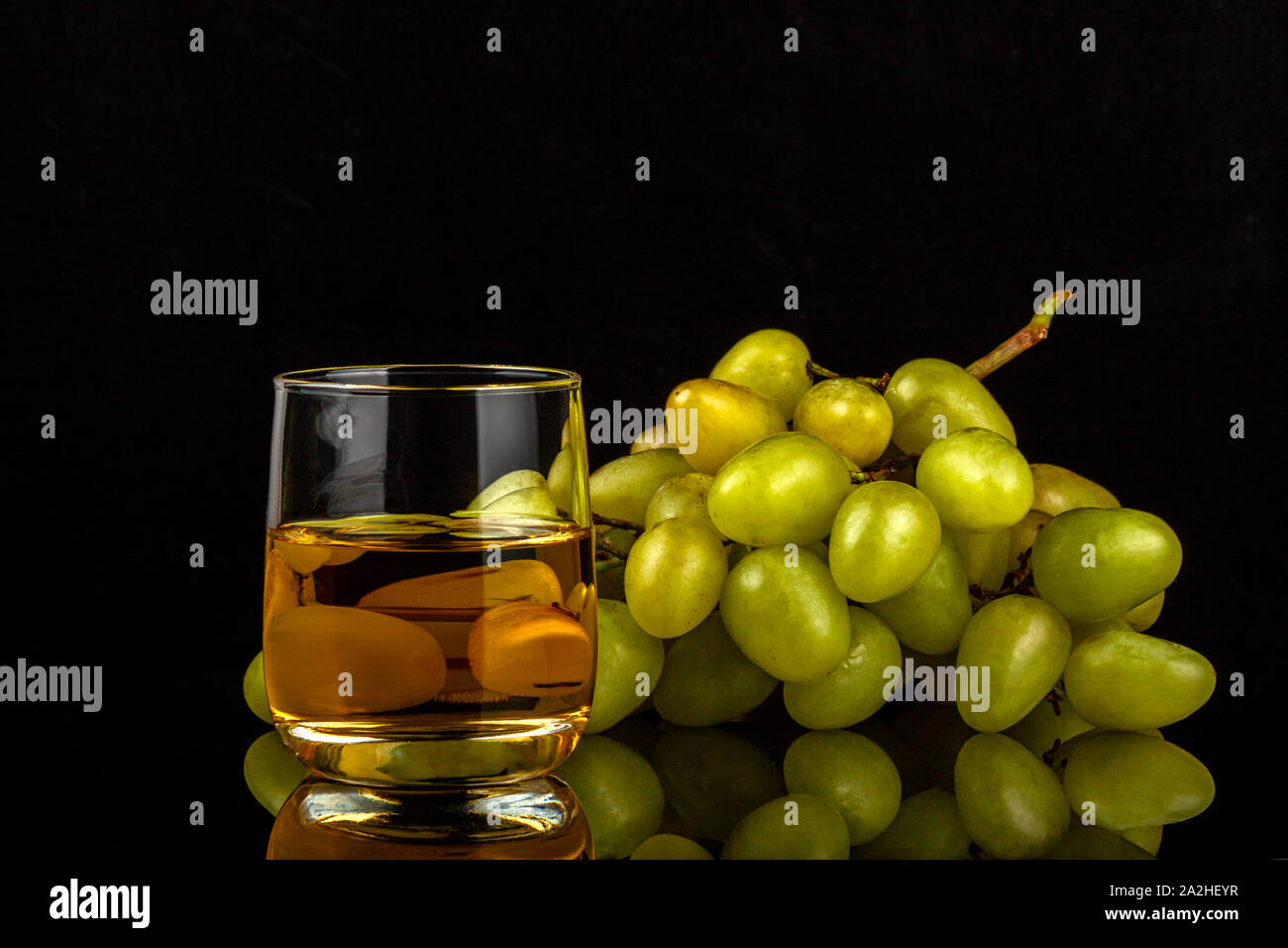 Two glasses of white wine and a bunch of grapes isolated on black Stock Photo