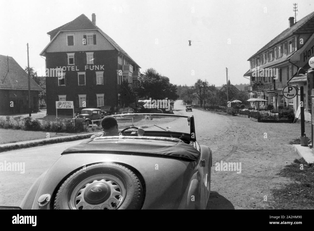 Ein Cabrio fährt am Hotel Funk im Schwarzwald vorbei, Deutschland 1930er Jahre. Convertible passing Funk's Hotel in the Black Forest region, Germany 1930s. Stock Photo