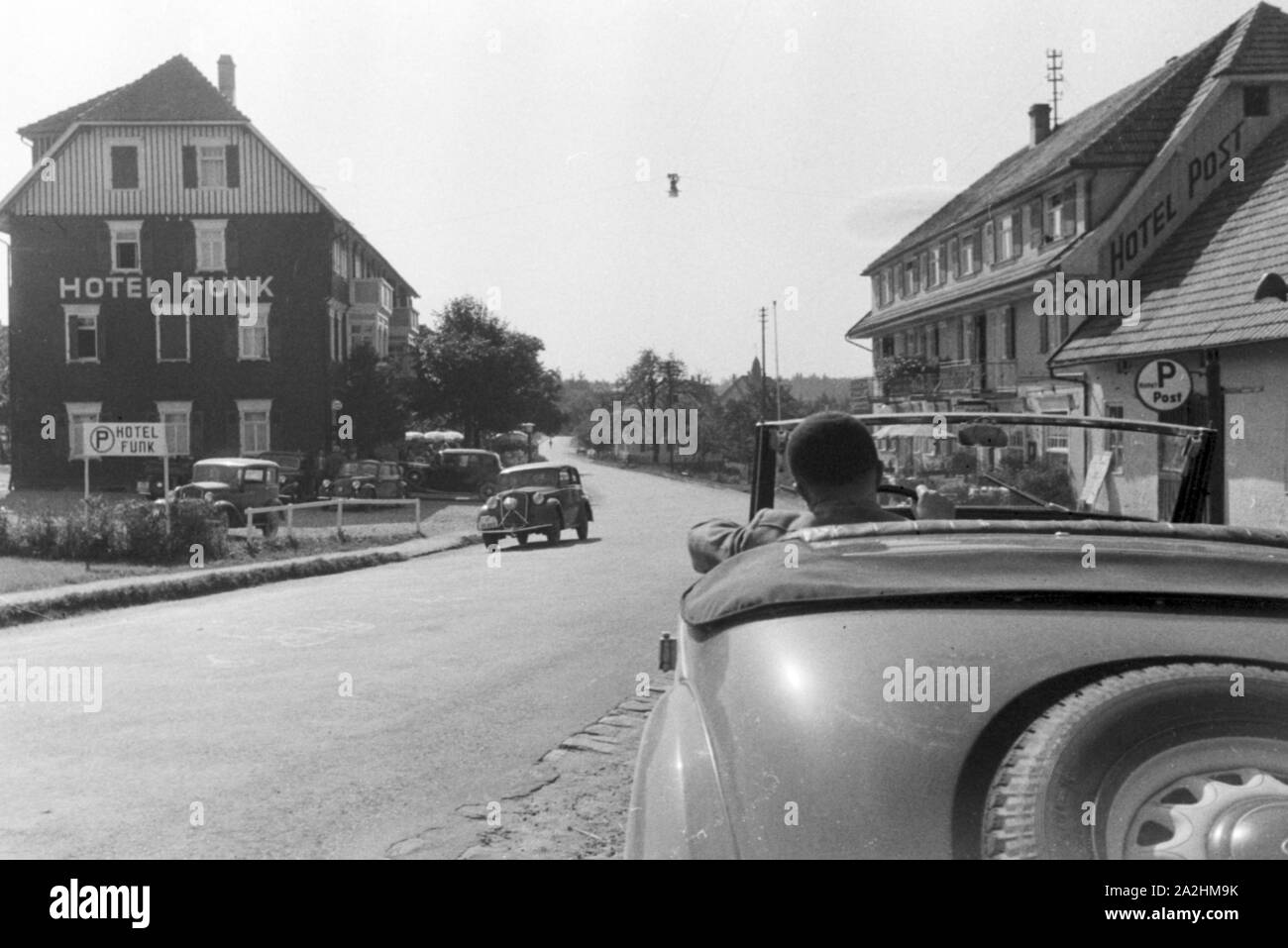 Ein Cabrio fährt am Hotel Funk im Schwarzwald vorbei, Deutschland 1930er Jahre. Convertible passing Funk's Hotel in the Black Forest region, Germany 1930s. Stock Photo