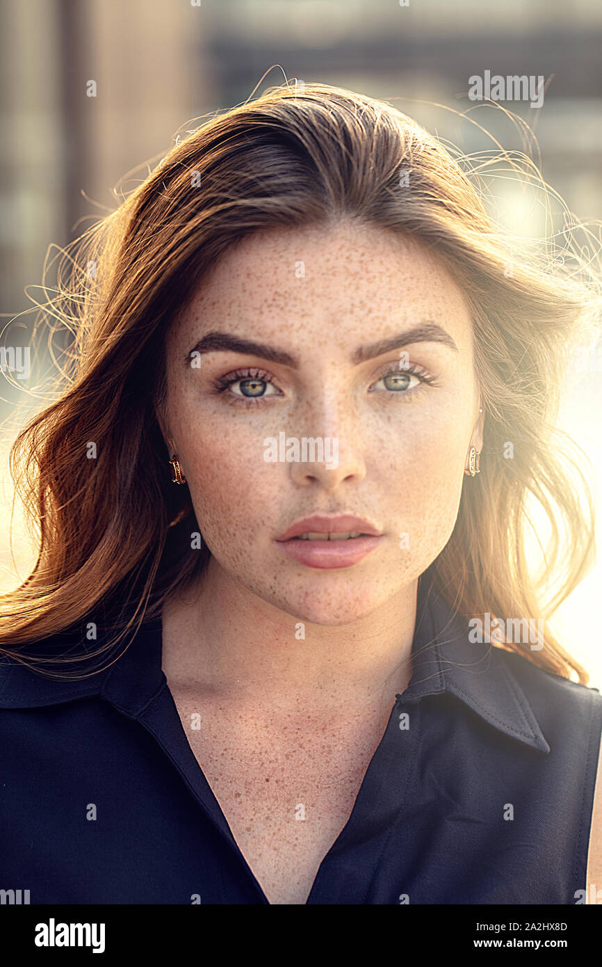 Portrait of beautiful young woman with freckles on her face , looking at camera. Girl with long hair and natural makeup. Stock Photo