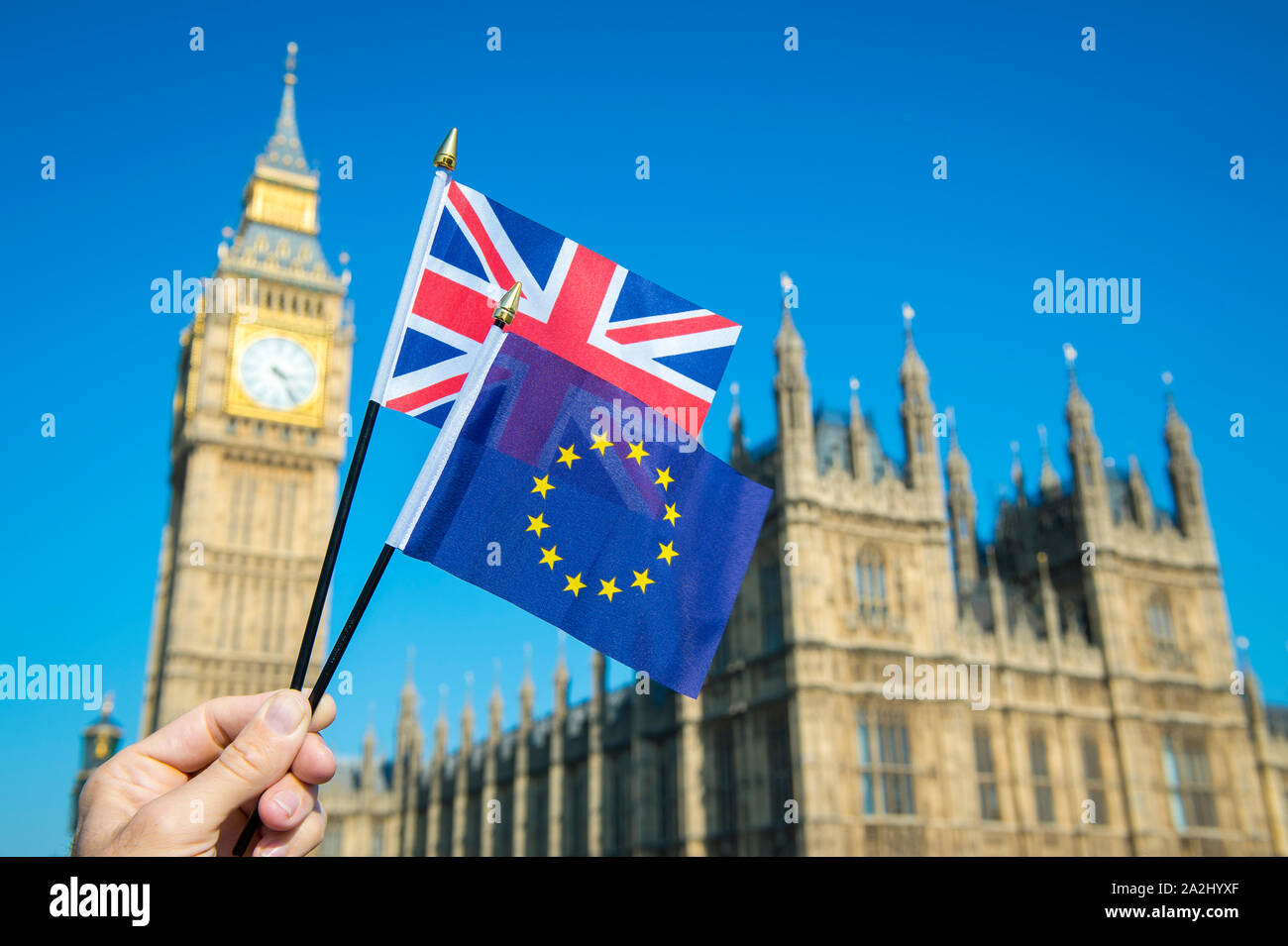 Hand waving European Union and British Union Jack flag in front of Big Ben and the Houses of Parliament at Westminster Palace, London, UK for Brexit Stock Photo