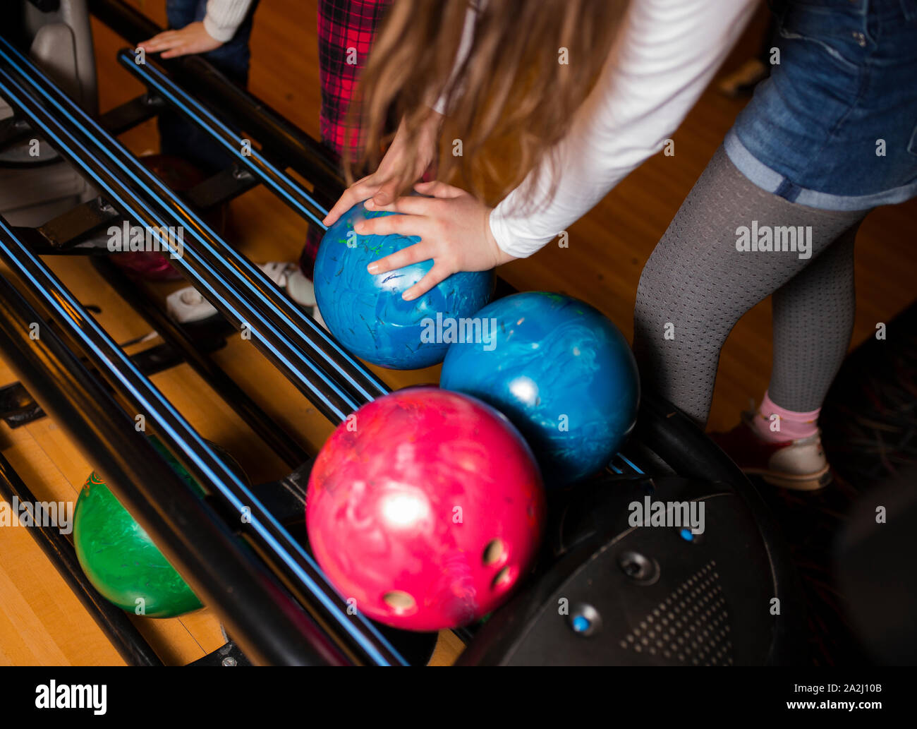 Closeup hand holding bowling ball against bowling alley Image. Cheerful Woman isready to play