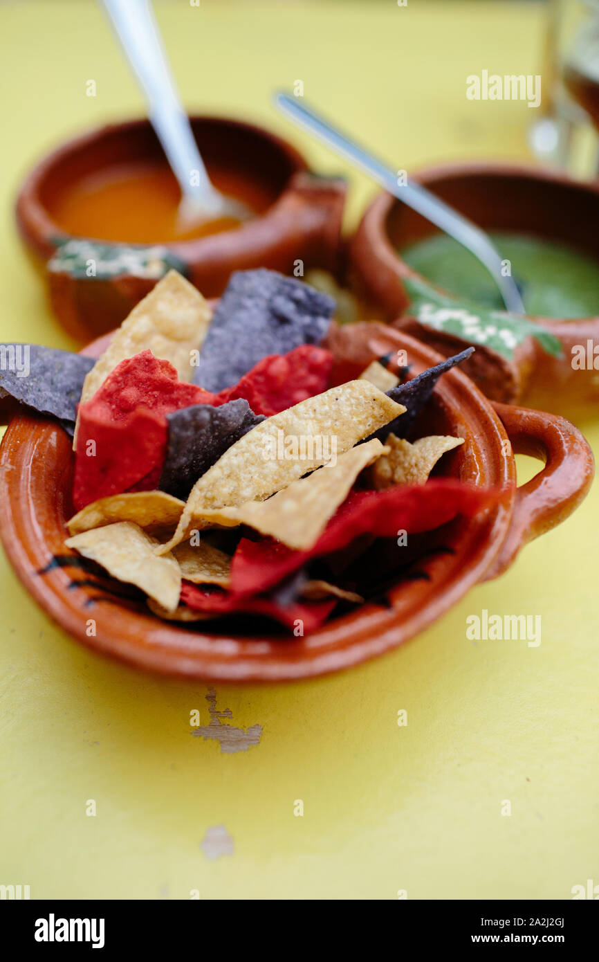 Mexican nachos on a yellow table. Green and red sauces on the