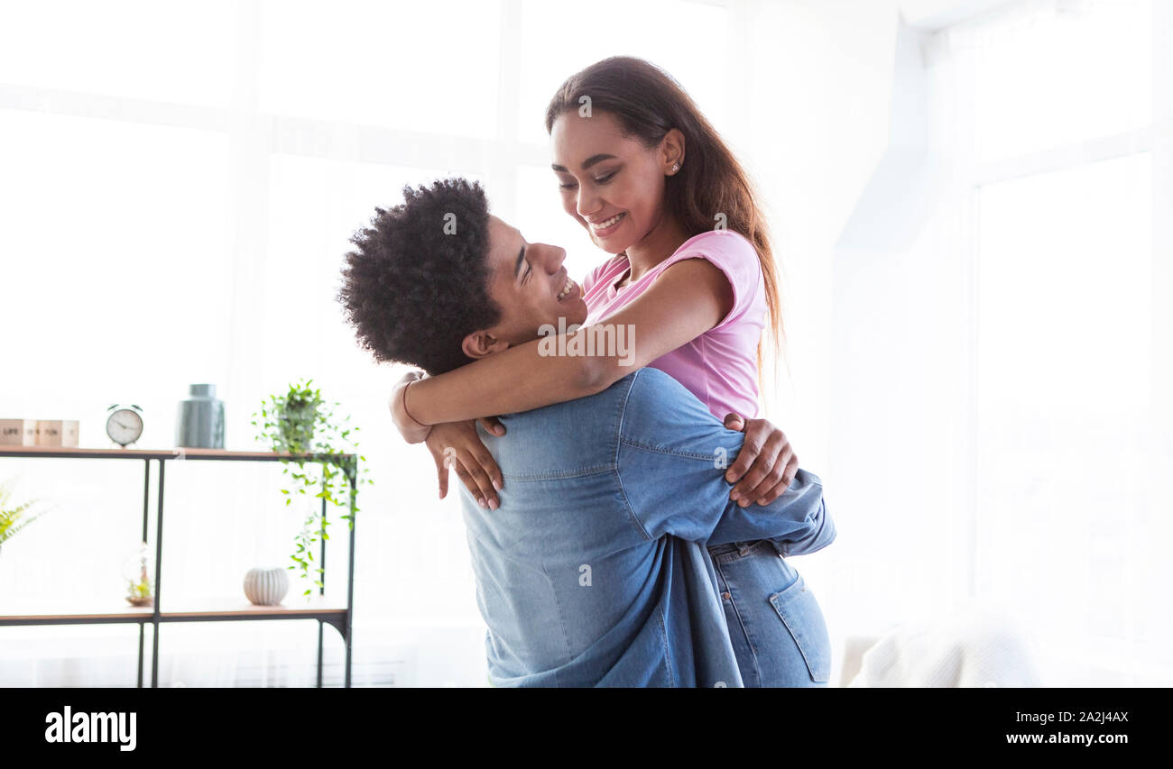 Guy hugging his girlfriend, holding her on hands at home Stock Photo