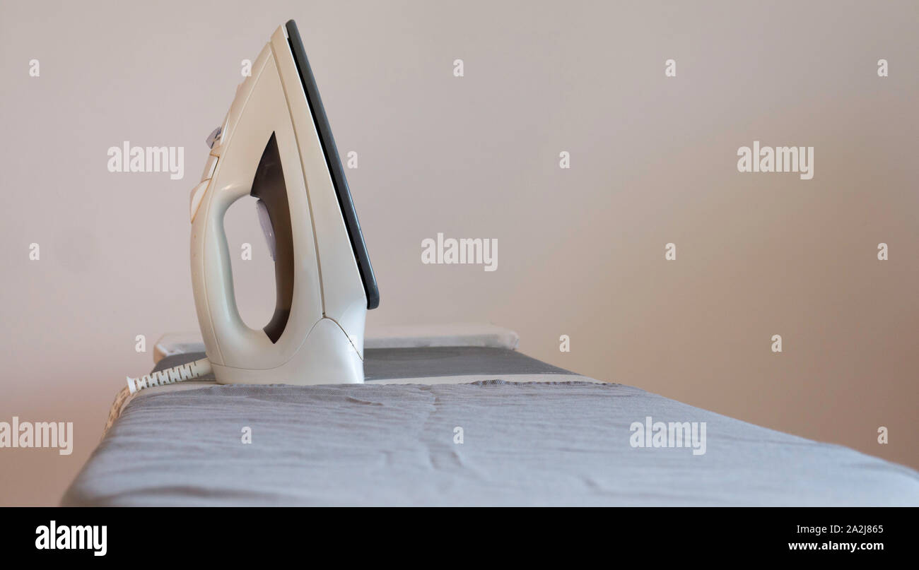 Electric iron on ironing board Stock Photo Alamy