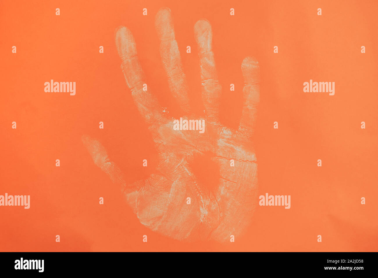 Close up beautiful white hand print on a coral orange background. Stock Photo