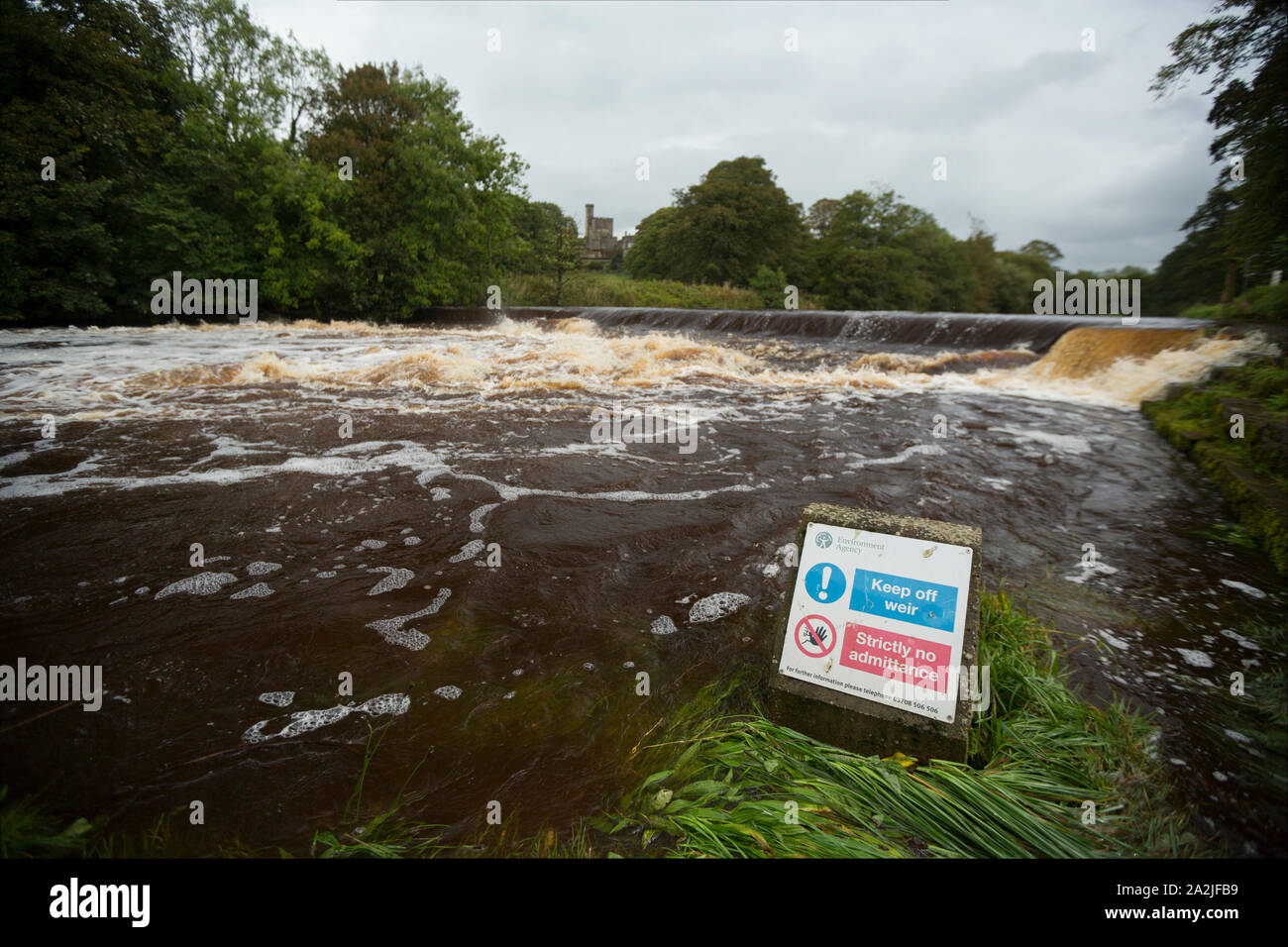 The River Wenning flowing over a weir after heavy rain in Sepember at Hornby village with Hornby Castle in the background. Not far downstream the Wenn Stock Photo