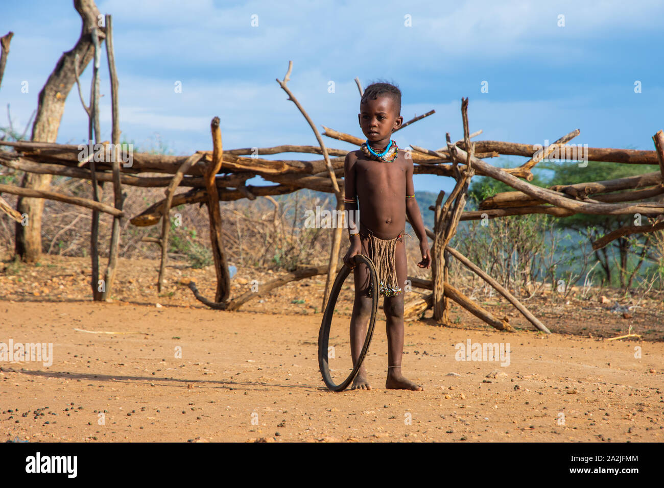 Turmi, Ethiopia - Nov 2018: Hamer tribe kid playing with the tire. Tire is a common toy in the region of Omo valley Stock Photo