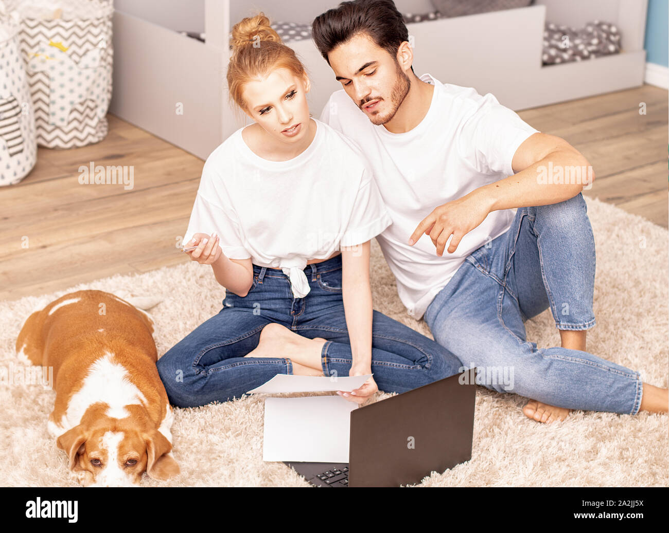 Young couple with cute beagle dog planning to arrange a children's room. Family concept. Stock Photo