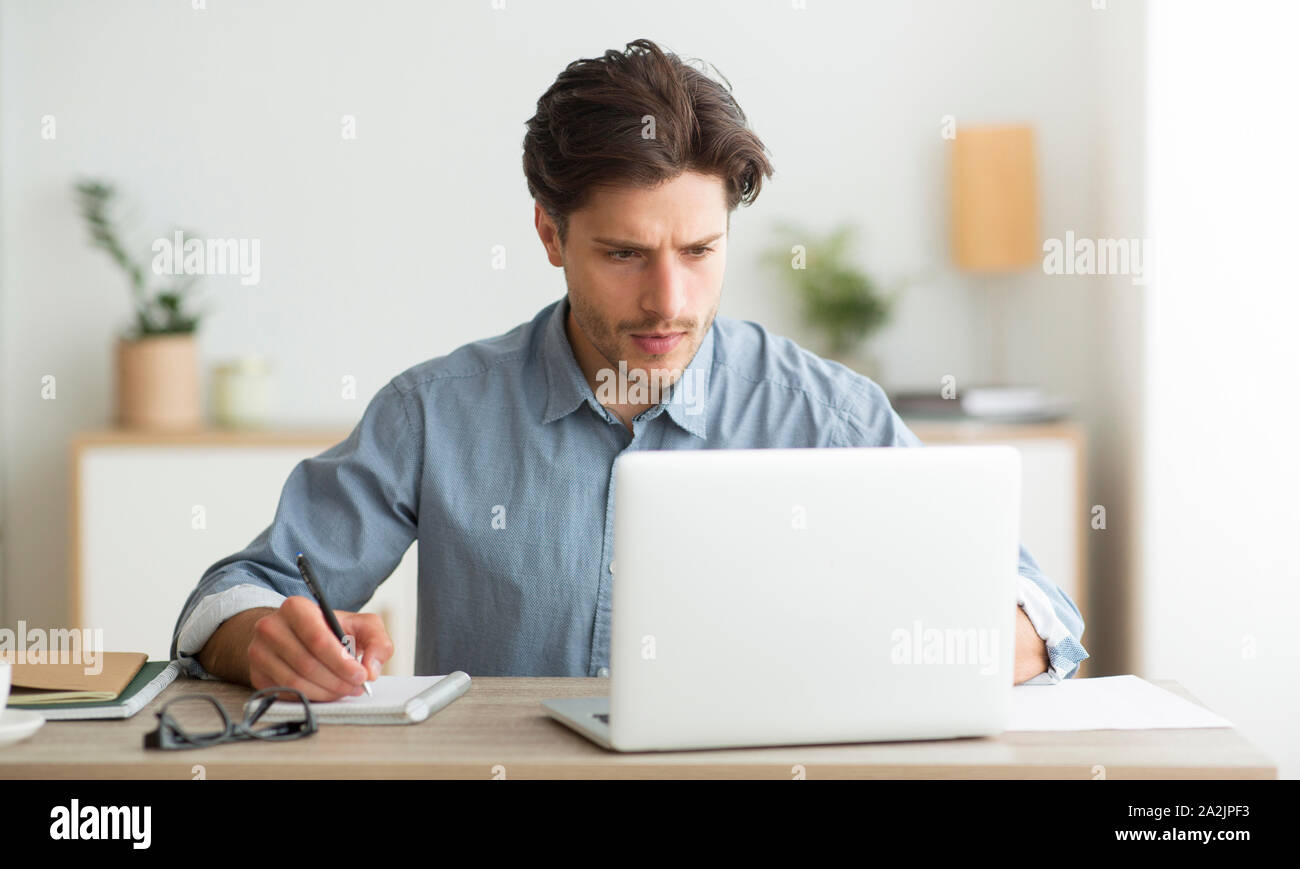 Young Entrepreneur Working On Laptop And Taking Notes Indoor Stock ...