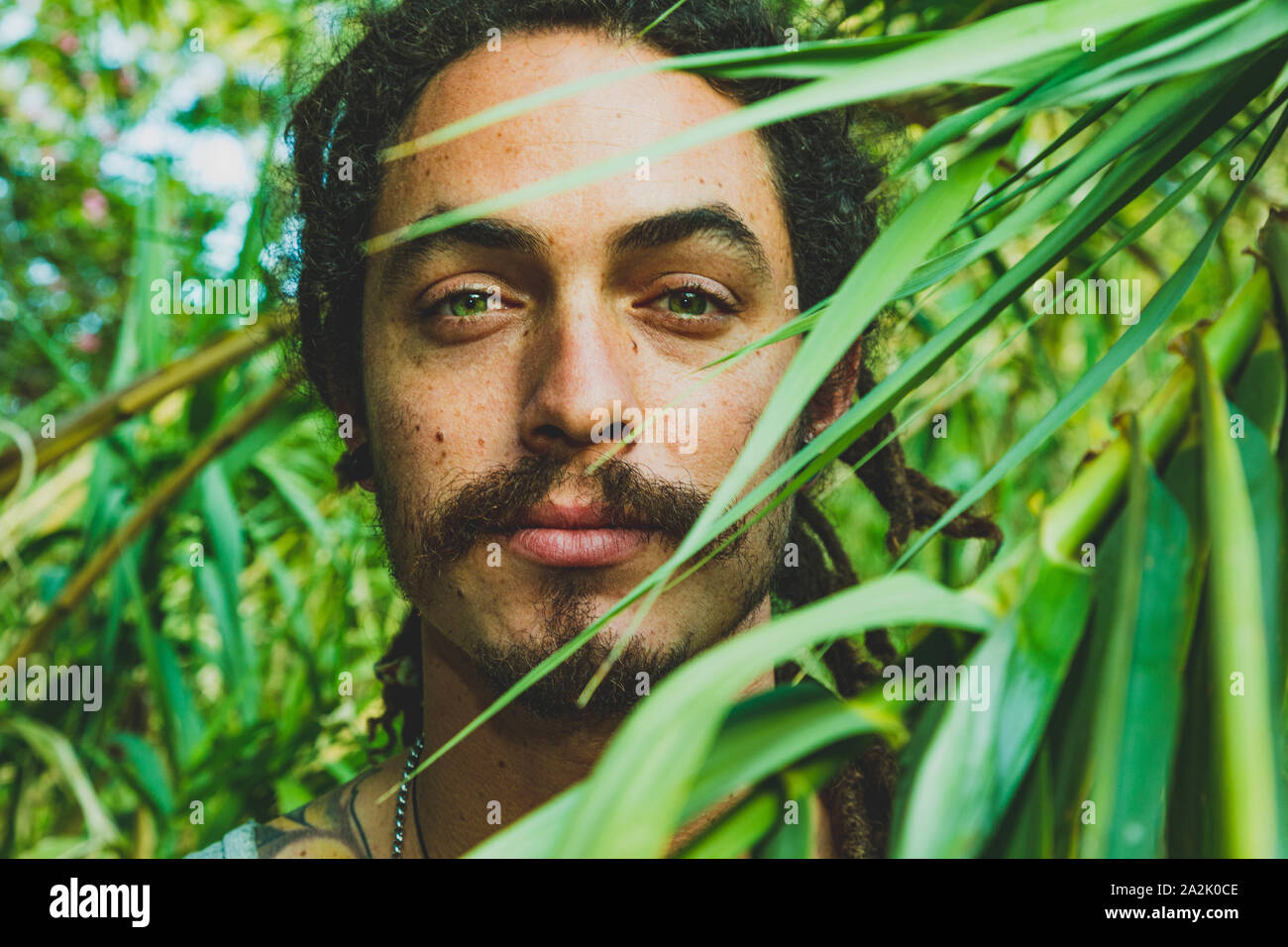 A handsome young man with green eyes and a vegetation background Stock Photo