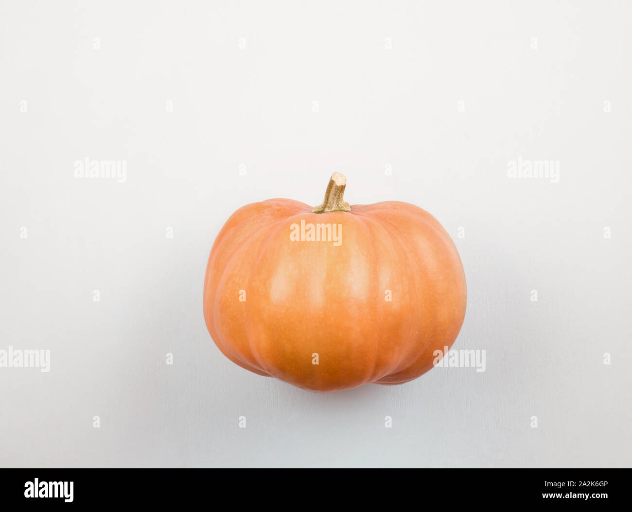 Orange pumpkin over white  background. Simple raw pumpkin with  stalk. Autumn harvesting nature concept.Flat lay,with copy space. Stock Photo