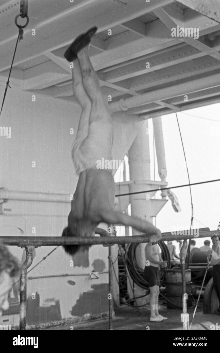 Einer der Männer der Besatung des Walfangfabrikschiffs 'Jan Wellem' hält sich durch Turnübungen fit, 1930er Jahre. A crew member of the factory vessel 'Jan Wellem' doing gymnastics at the parallel bars, 1930s. Stock Photo