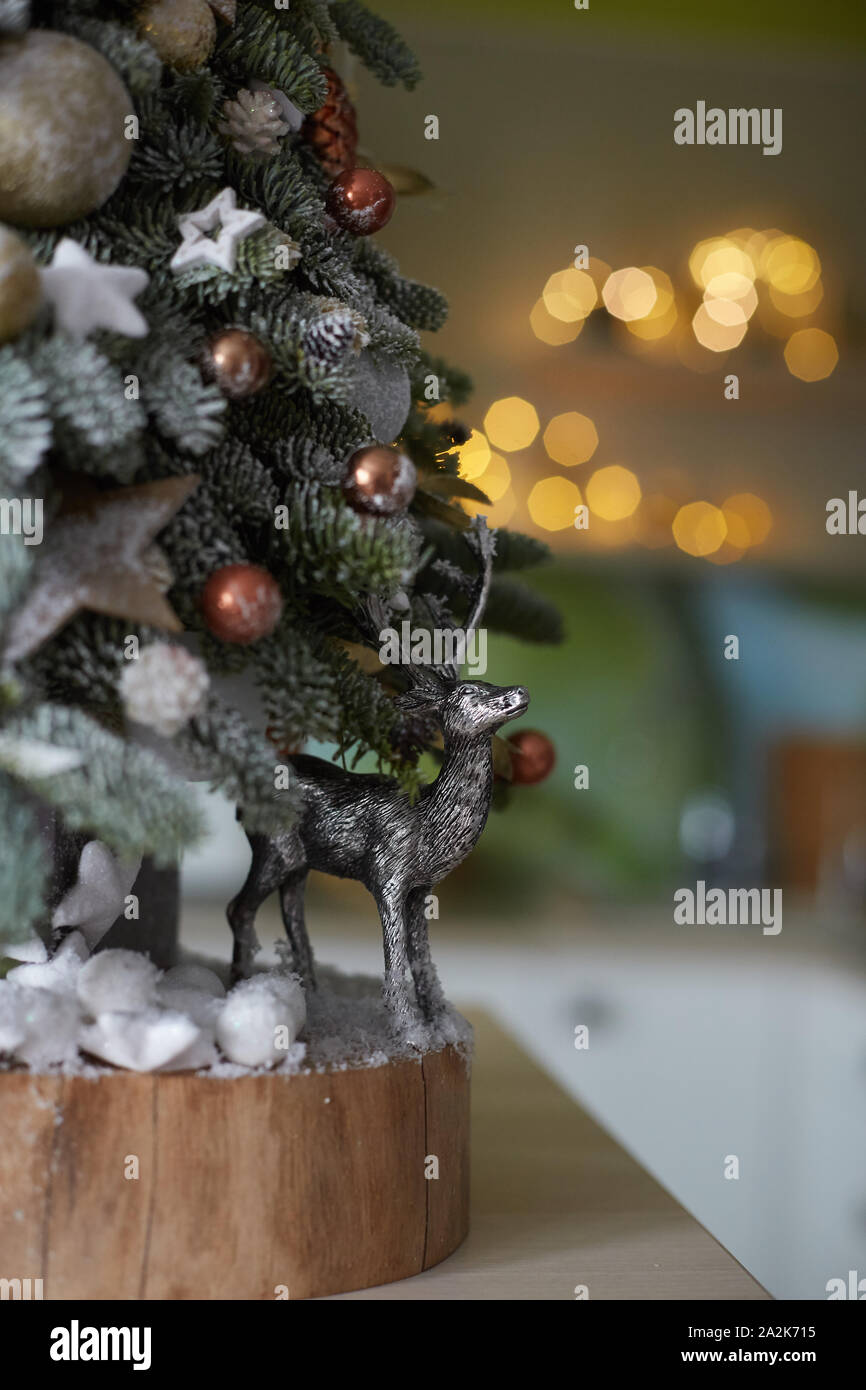 Small silver deer under the small artificial Christmas tree. Artificial