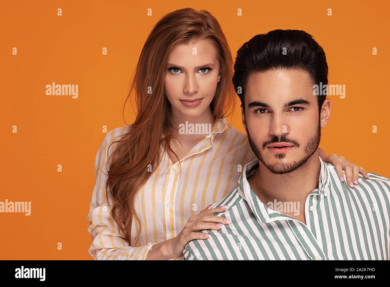 Beautiful young couple posing together on yellow studio background. Facial expression, human emotions concept. Stock Photo