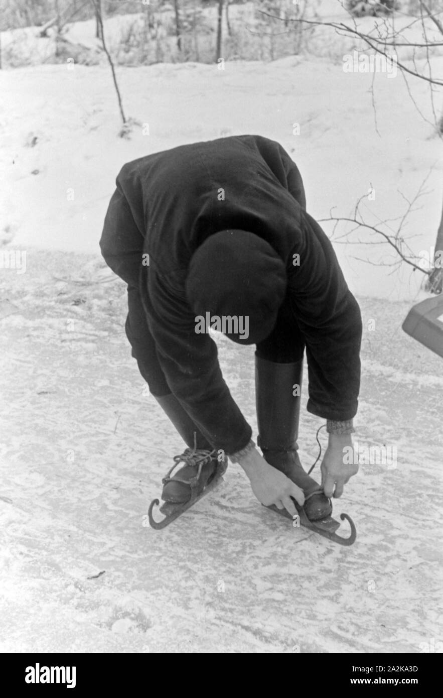 Ein Mann schnallt sich Schlittschuhkufen an im Spreewald, Deutschland 1930er Jahre. A man putting on his ice skate runners at Spreewalad area, Germany 1930s. Stock Photo