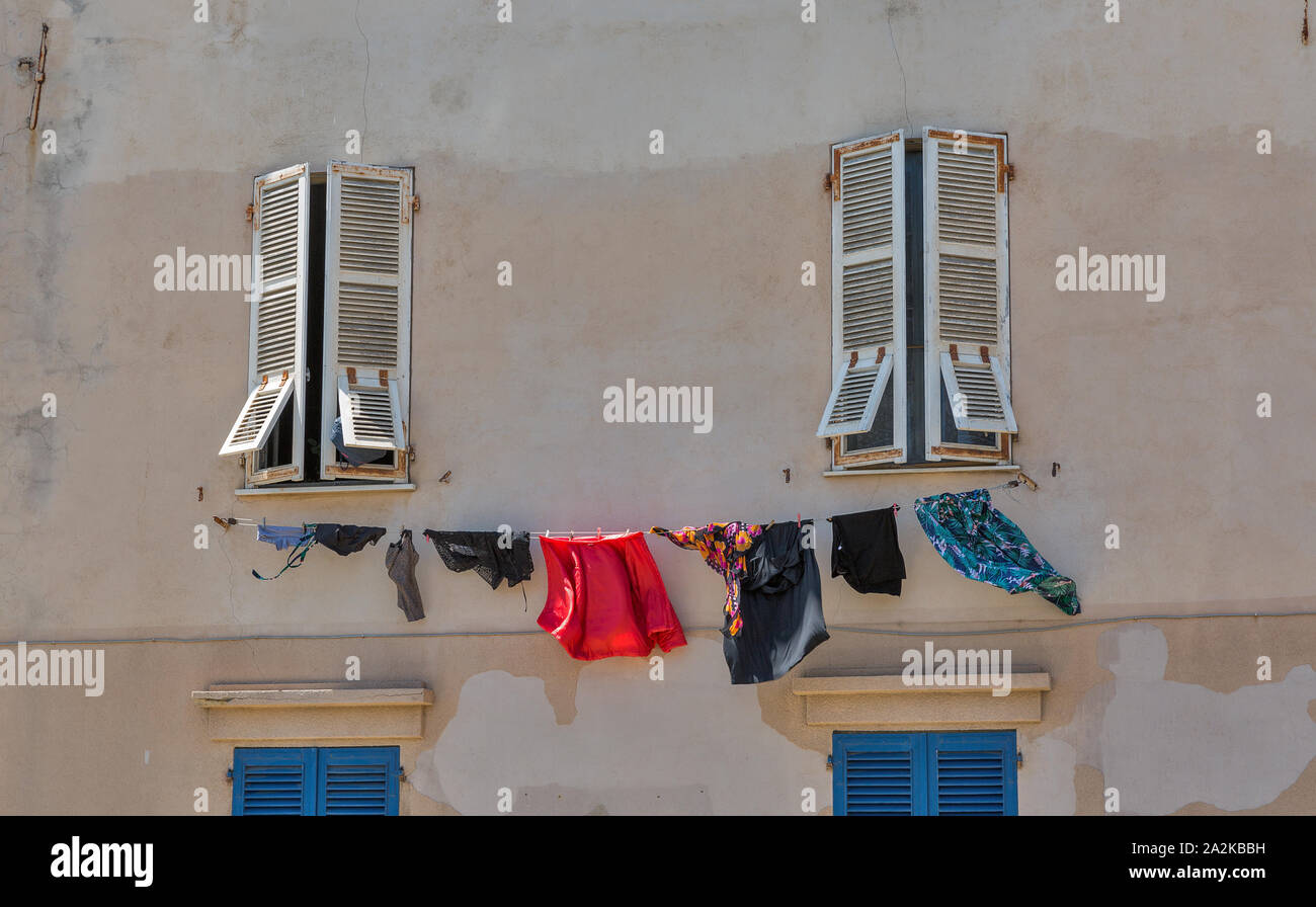 Old typical building facade wall with washing hanging closeup in Ajaccio, Corsica island, France. Stock Photo