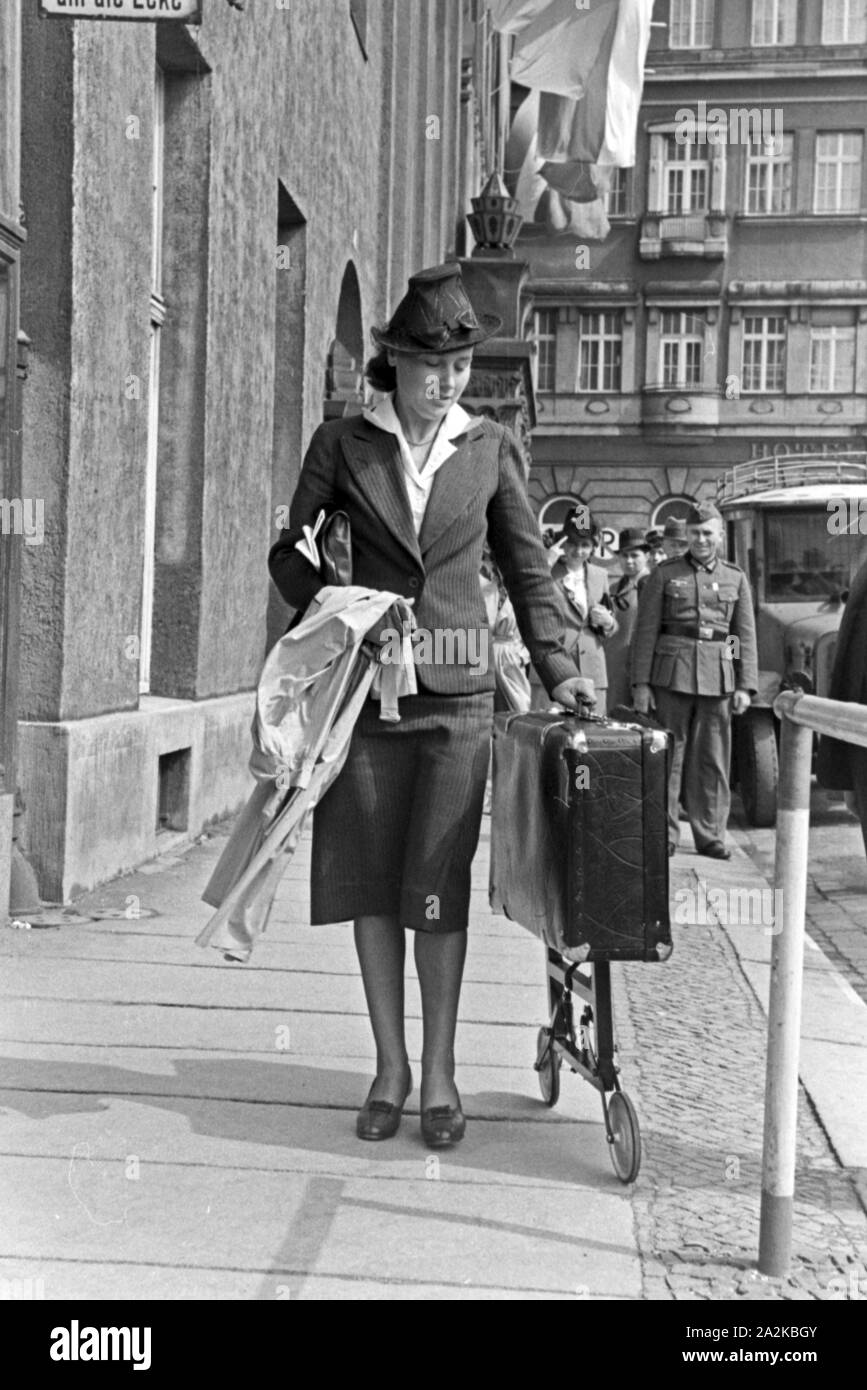 Eine Frau mit einem Koffer auf Rollen bei der Messe Leipzig, Deutschland 1940er Jahre. A woman with a suitcase on wheels at Leipzig trade show, Germany 1940s. Stock Photo