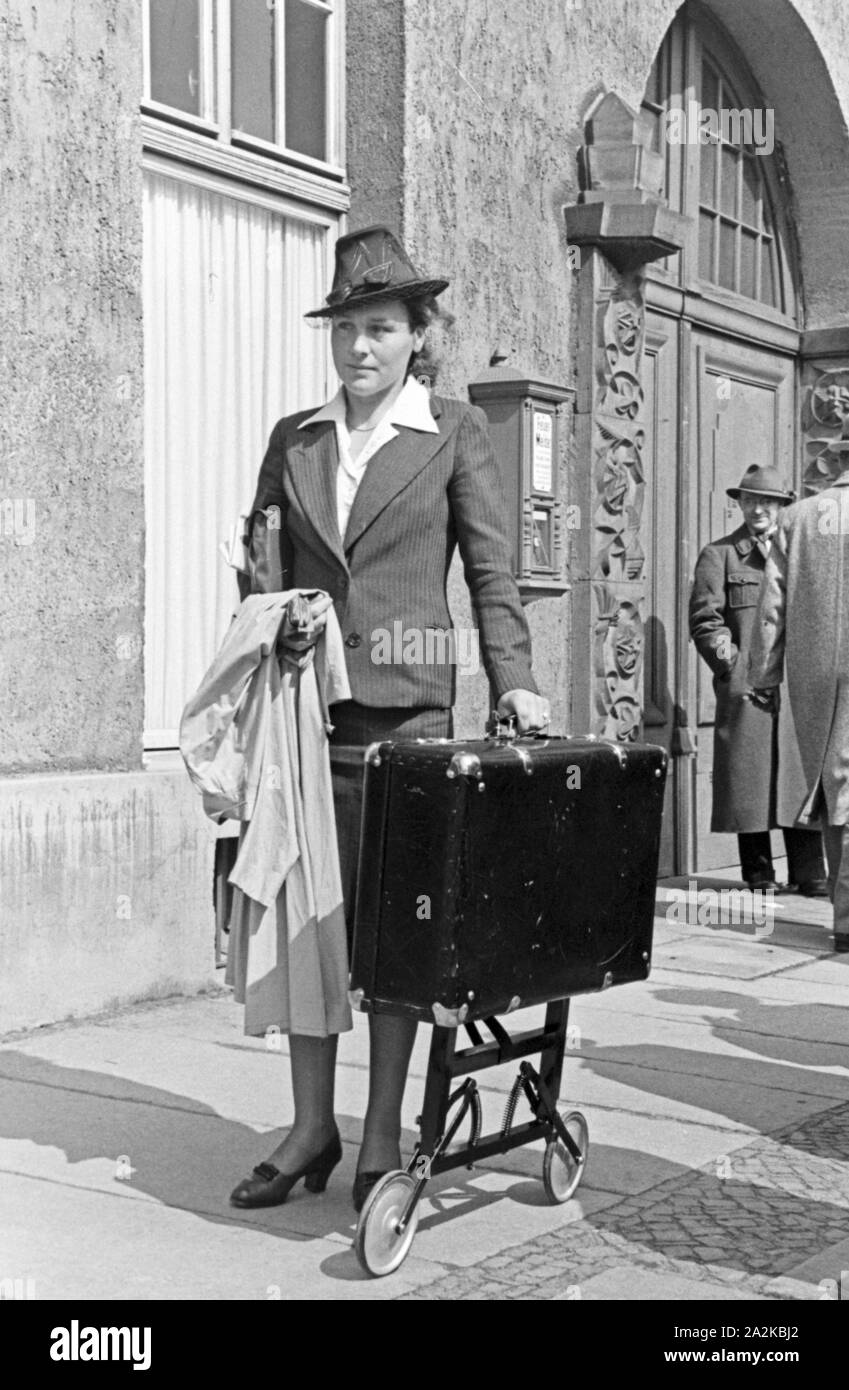 Eine Frau mit einem Koffer auf Rollen bei der Messe Leipzig, Deutschland 1940er Jahre. A woman with a suitcase on wheels at Leipzig trade show, Germany 1940s. Stock Photo