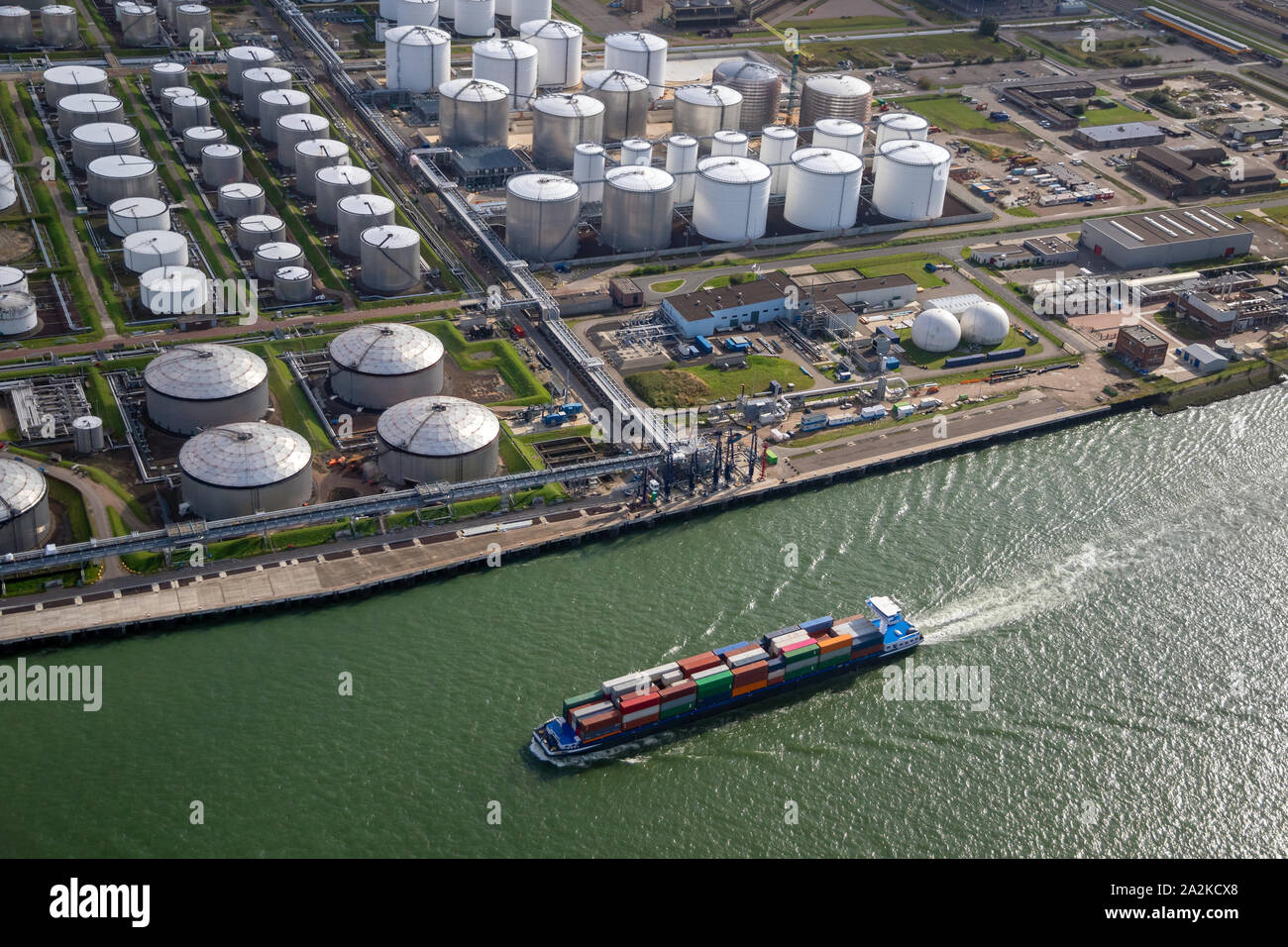 Aerial view of a ship pasing an oil storage silo terminal port. Stock Photo