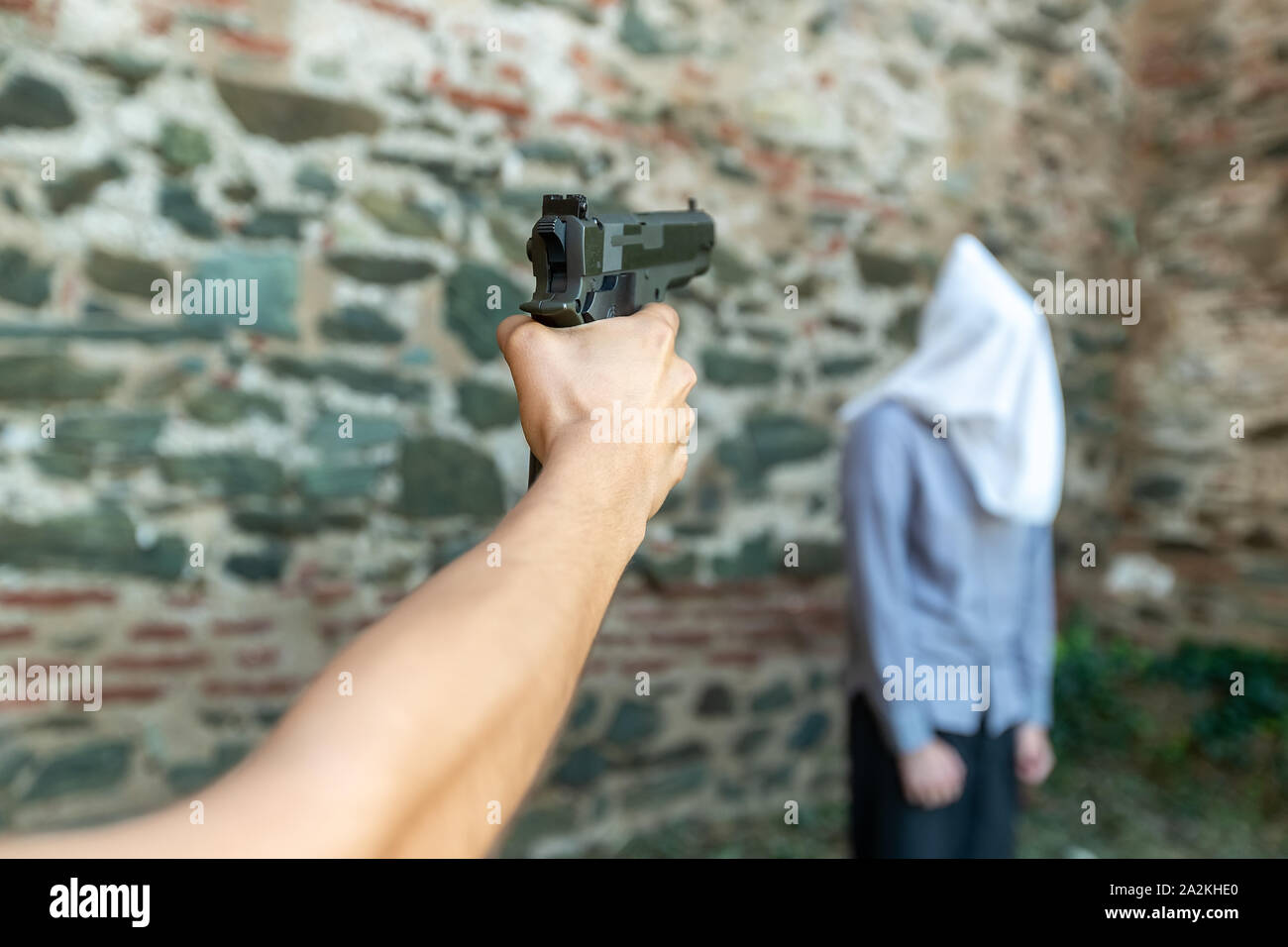 a hand with a gun marks a man with a hood on his head. selective focus Stock Photo