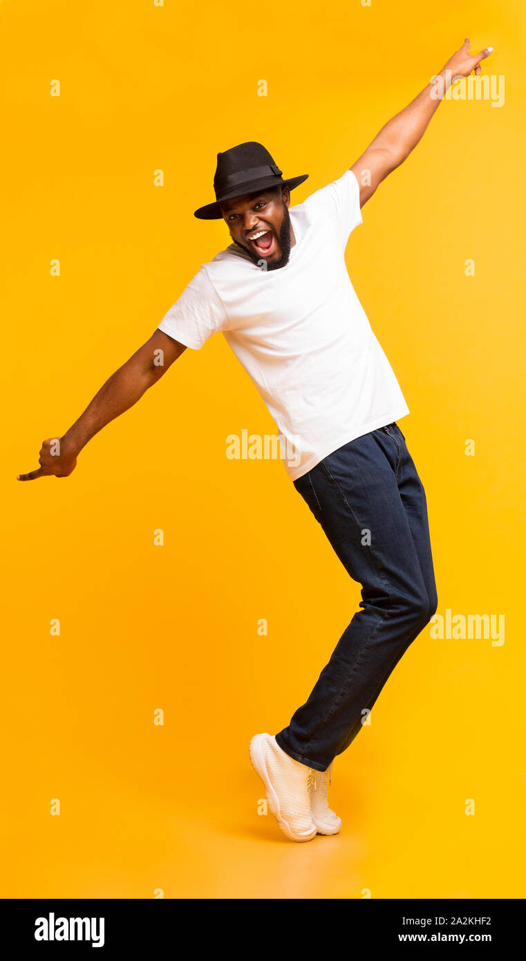 Funny Black Guy Fooling, Standing on Tiptoes Over Yellow Background Stock Photo
