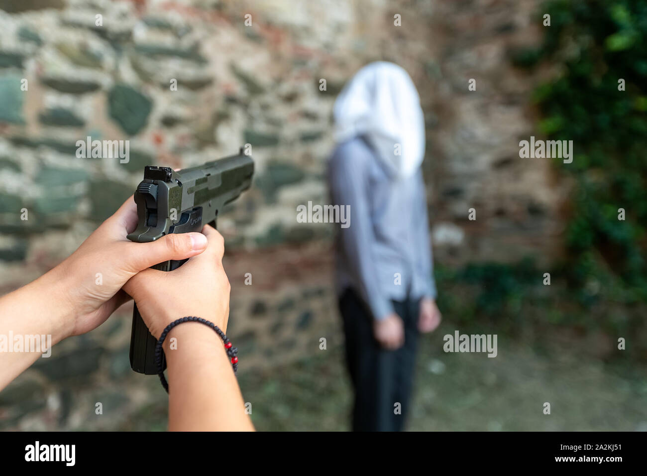 a hand with a gun marks a man with a hood on his head. selective focus Stock Photo