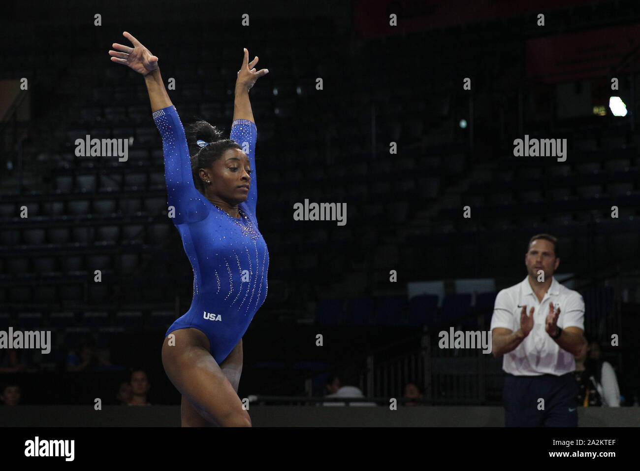 Stuttgart, Germany. 1st Oct, 2019. Gymnast Simone Biles from the USA during the podium training day at the 2019 World Artistic Gymnastics Championships in Stuttgart, Germany. Biles after landing a double-twisting double back dismount, a skill she hopes will be named after her, while coach Laurent Landi watches. Melissa J. Perenson/CSM/Alamy Live News Stock Photo