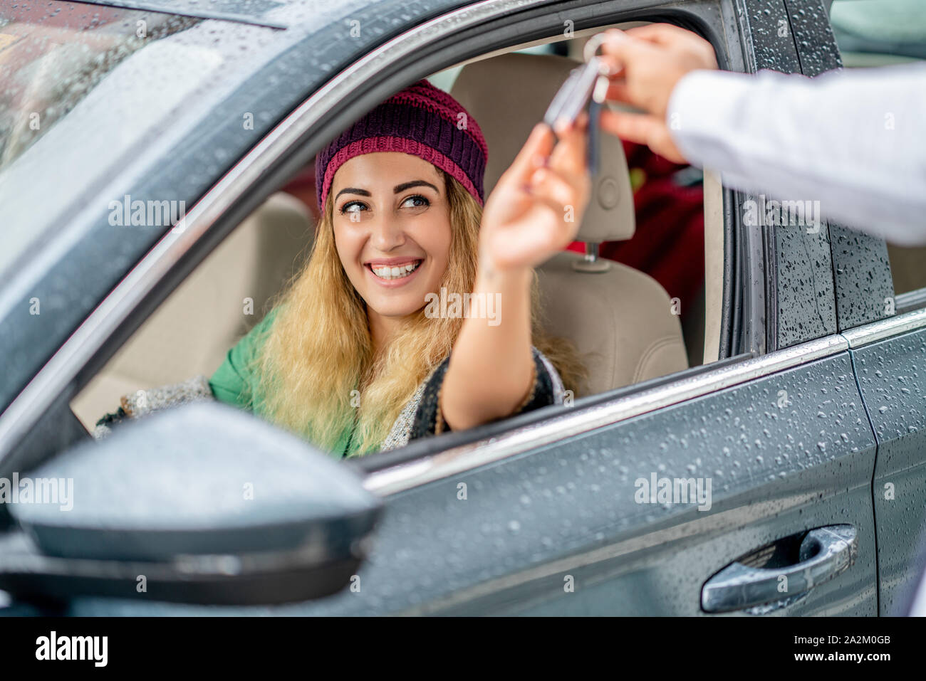 young woman take the key from valet to drive her car. Stock Photo