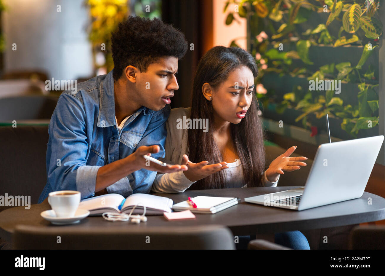 Angry students looking at laptop with furious faces Stock Photo