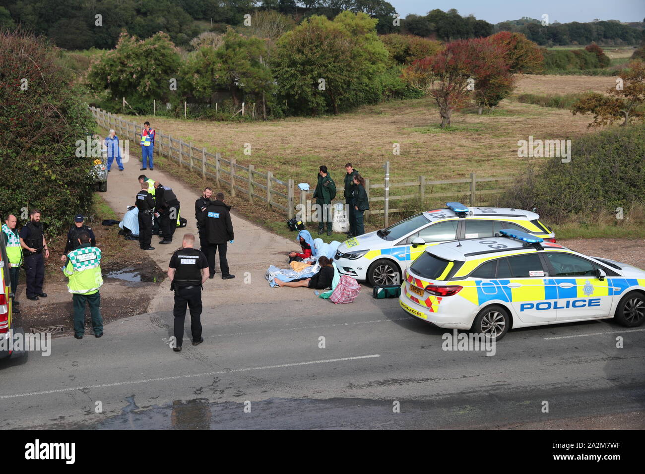 MIGRANTS SITTING BY A POLICE CAR COVERED BY BLANKETS JUST AFTER ARRIVING AT A SOUTH COAST BEACH IN OCTOBER 2019 WITH IMMIGRATION ENFORCEMENT PRESENT Stock Photo