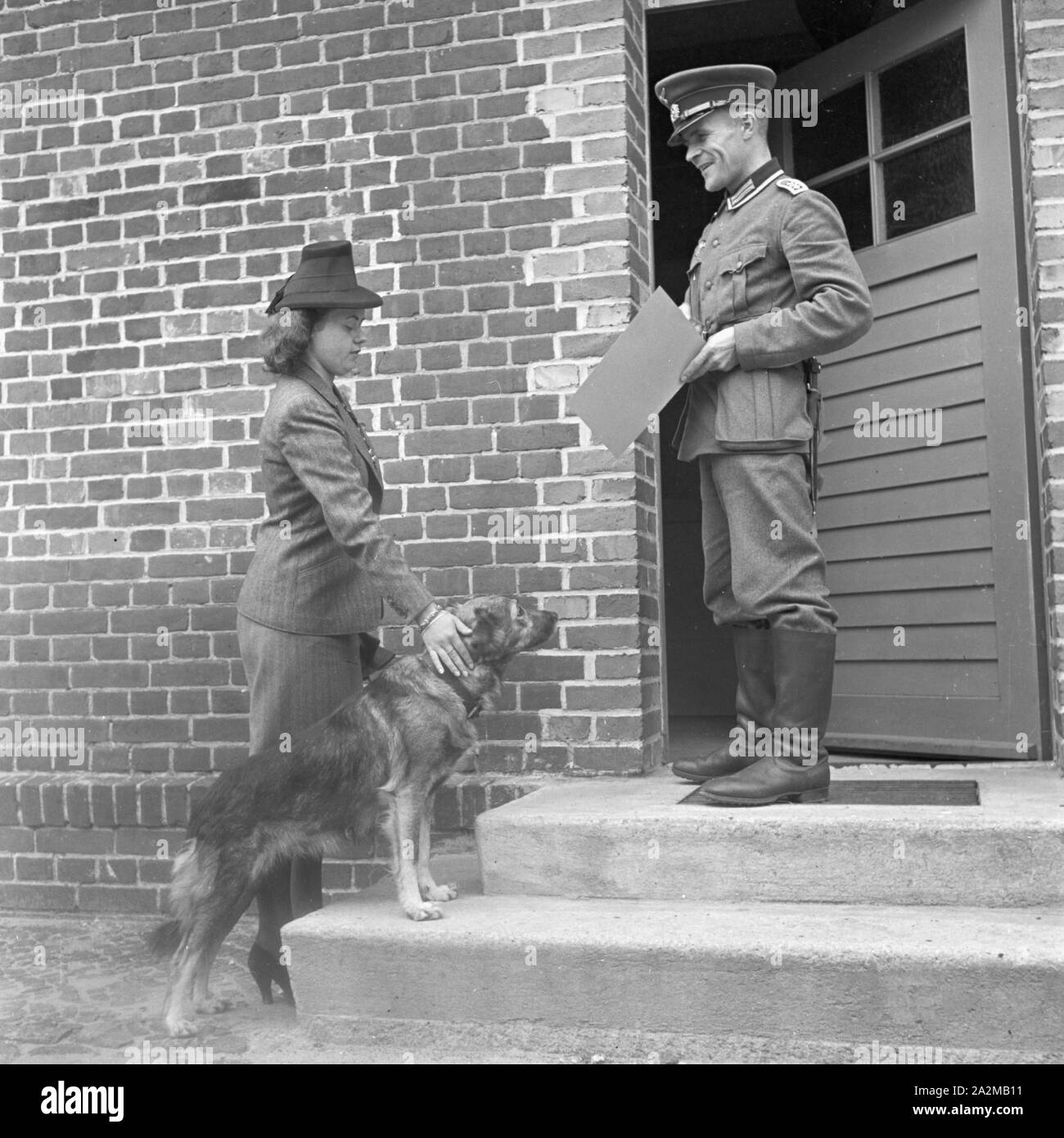 Original-Bildunterschrift: Der Hund Senta wird aufgrund seines Gestellungsbefehls von seinem Frauchen in der Lehranstalt für Heereshunde abgeliefert, wenn auch schweren Herzens, Deutschland 1940er Jahre. Senta the dog is brought to the army pet obedience school because it got its induction order, Germany 1940s. Stock Photo