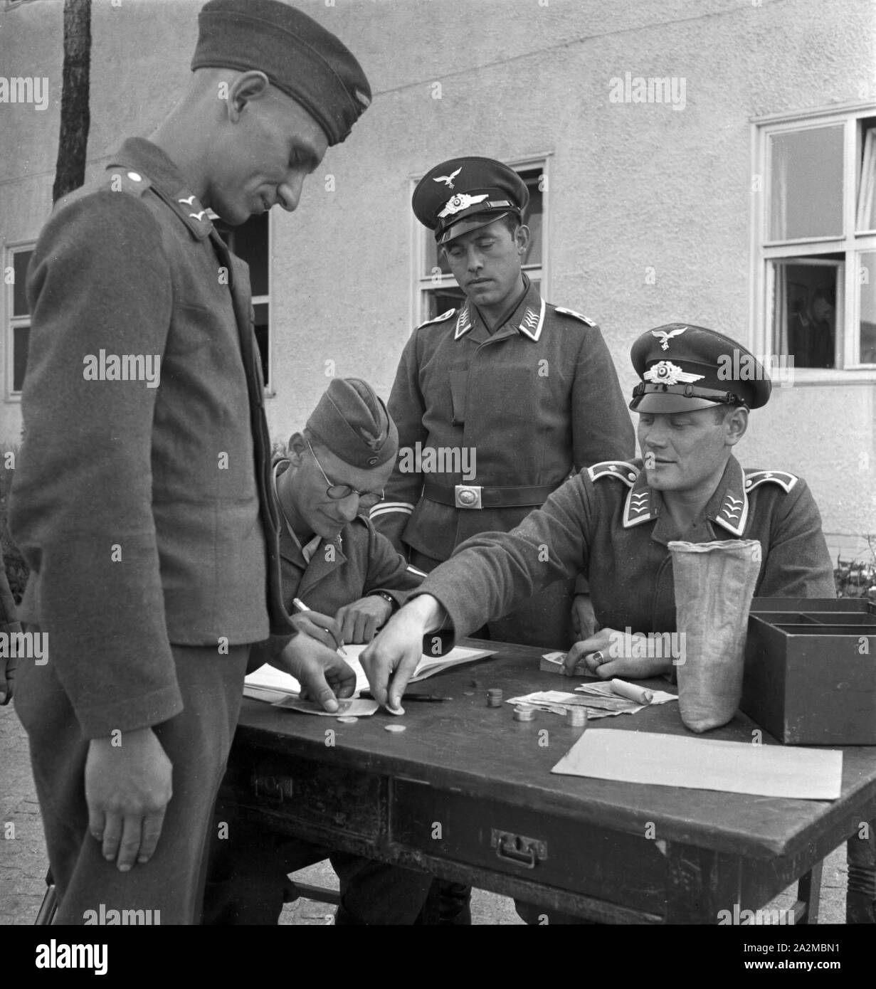 Original-Bildunterschrift: Das 'Geld holen' ist auch für den Soldaten immer eine angenehme Sache, Deutschland 1940er Jahre. Getting money is something fine for soldiers, Germany 1940s. Stock Photo