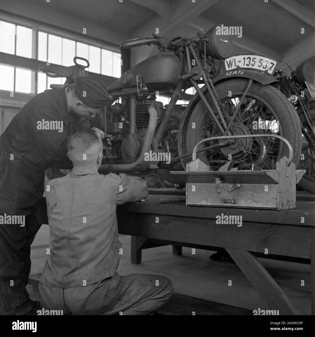 Original-Bildunterschrift: Arbeiten in der Kraftfahr-Werkstatt geben dem Soldaten die letzten Kenntnisse in der Pflege der Maschine, Deutschland 1940er Jahre. Working at the garage giving the soldier the necessary maintenance knowledge, Germany 1940s. Stock Photo