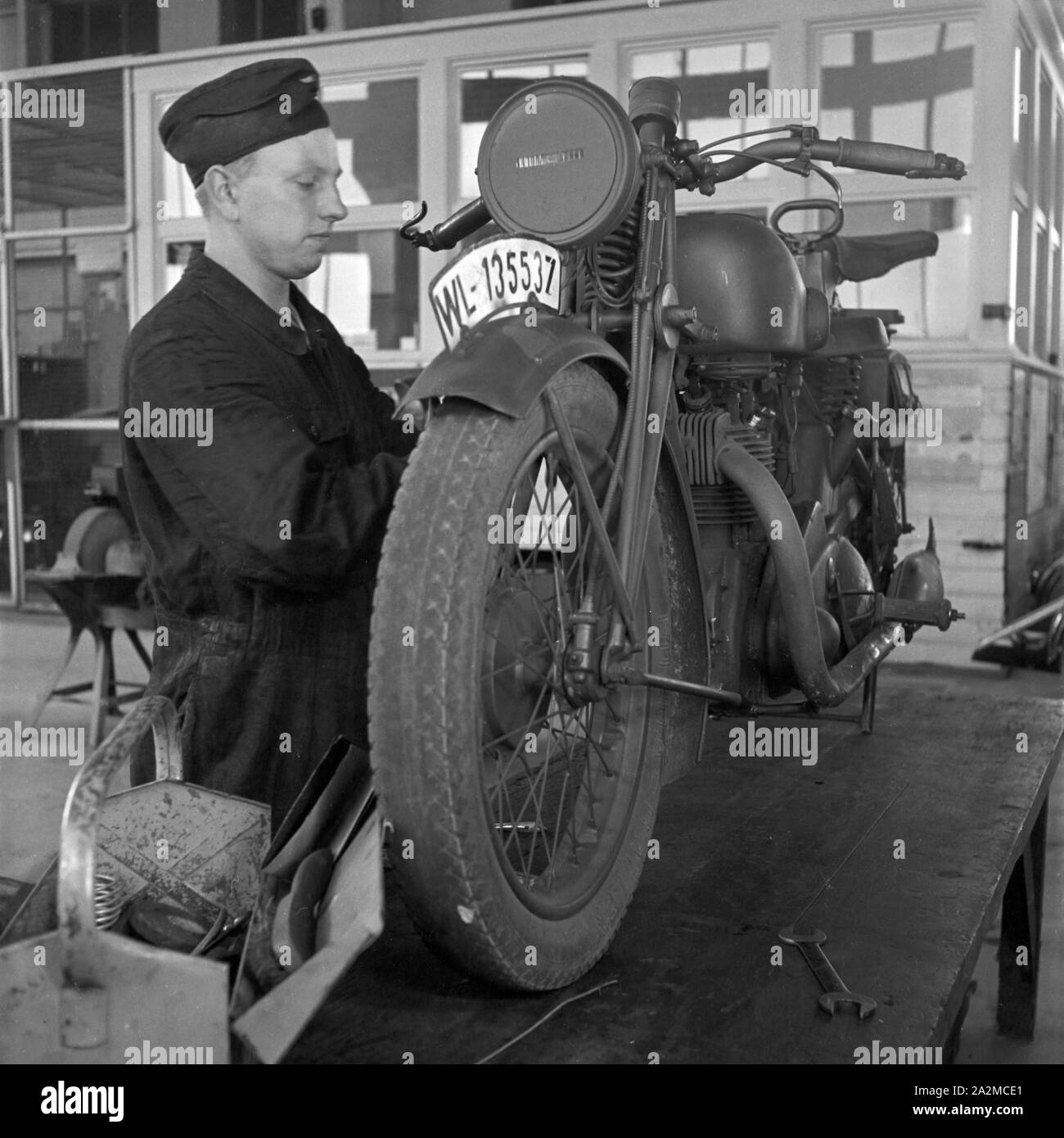 Original-Bildunterschrift: Ausbildung als Kraftfahrer - auch in der Werkstatt lernt der Nachrichtenmann den Motor gründlich kennen, Deutschland 1940er Jahre. At the garage the soldier of a signal corps unit checking the engine of his motorbike, Germany 1940s. Stock Photo