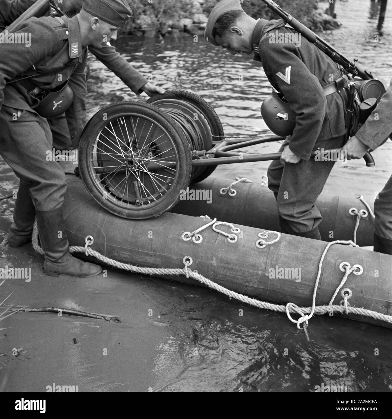 Original-Bildunterschrift: Der Kabelwagen wird auf dem Boot befestigt, Deutschland 1940er Jahre. The cable drum is loaded to the rubber boat, Germany 1940s. Stock Photo