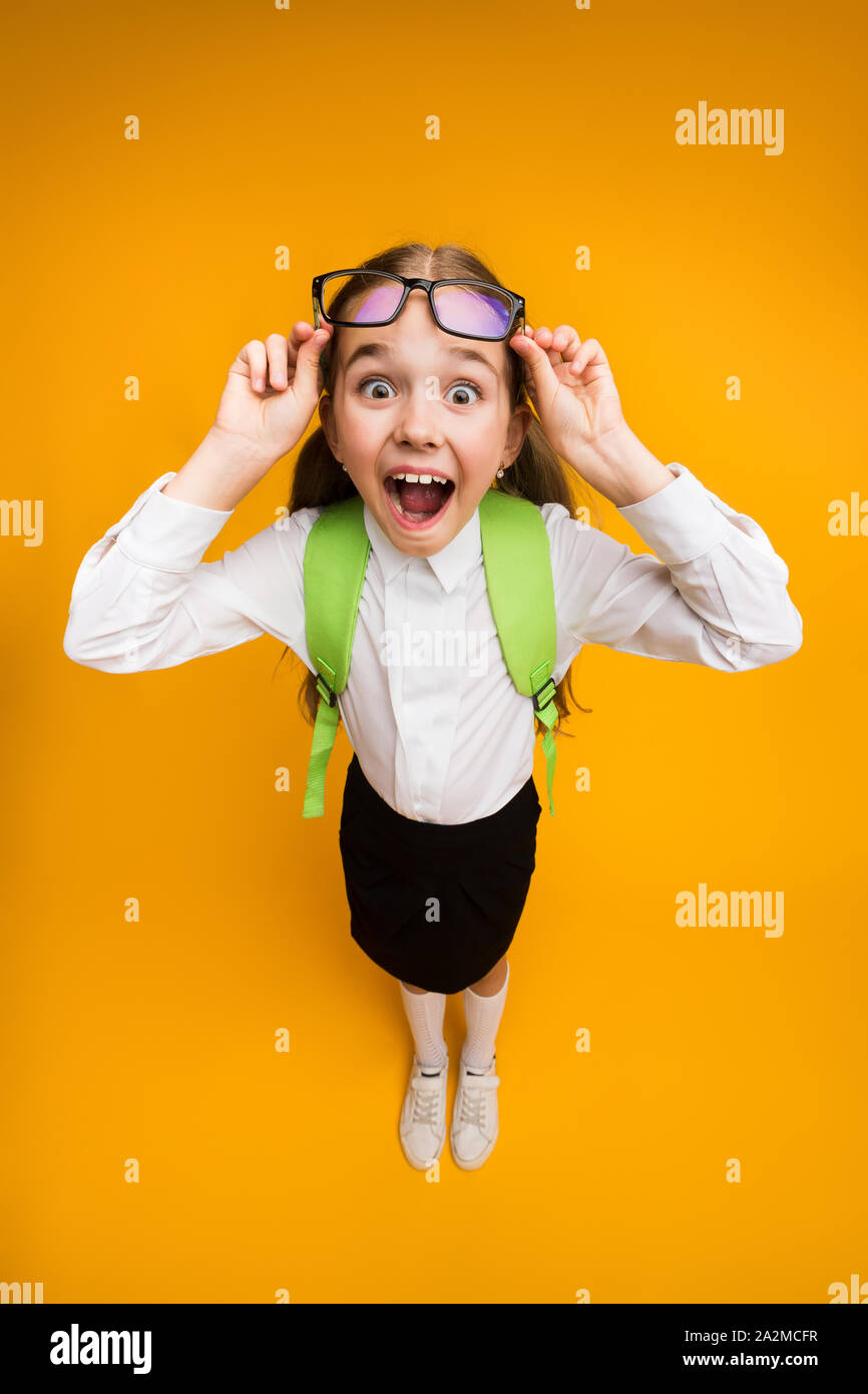 Overjoyed Schoolgirl Wearing Eyeglasses Posing On Yellow Background Stock Photo