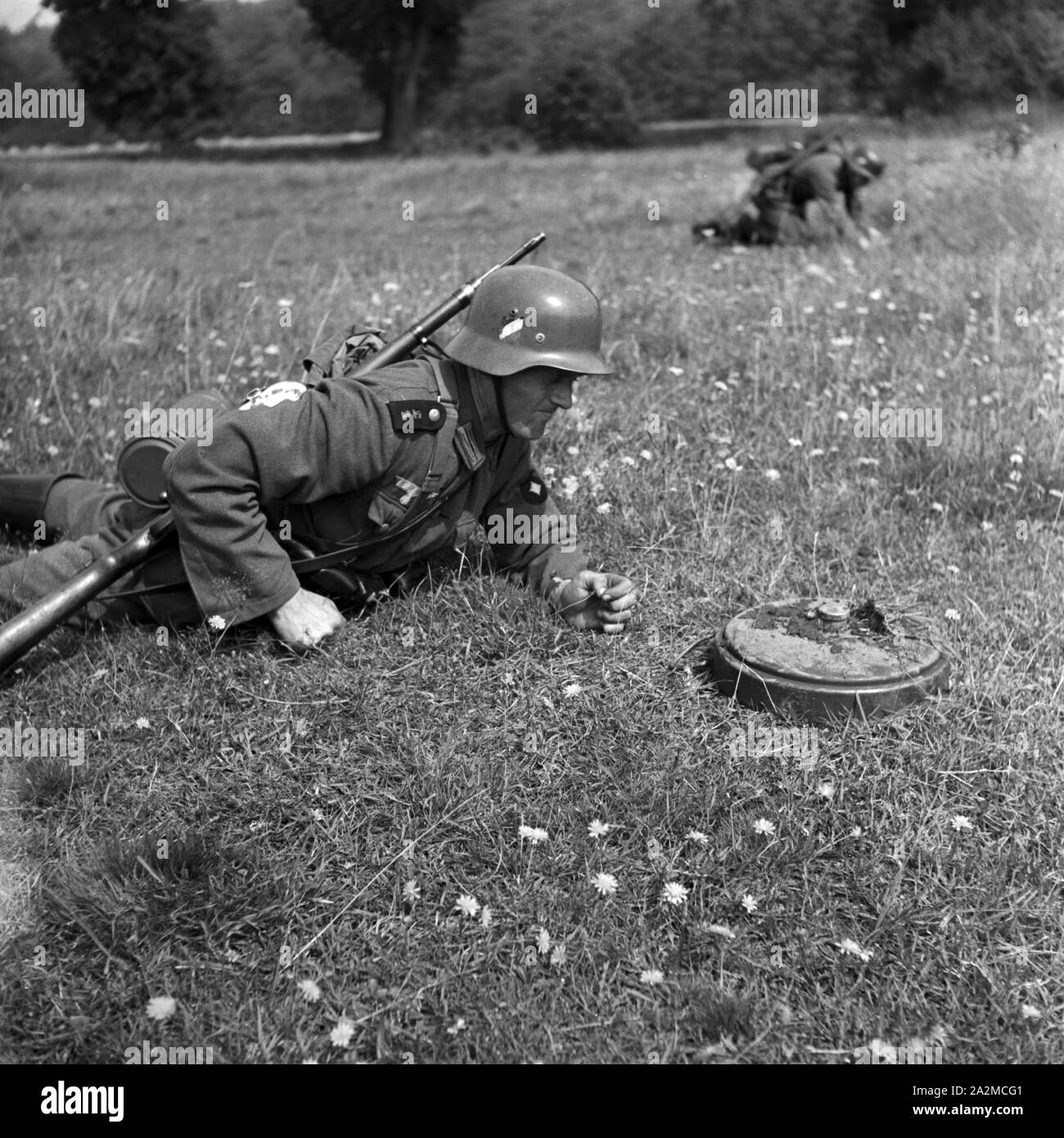 Original-Bildunterschrift: Pioniere stürmen beim Legen einer Minensperre gegen Panzer in die befohlene Stellung; dort angekommen erwarten sie den Befehl zum Entsichern, Deutschland 1940er Jahre. Soldiers of a military engineering unit waiting to unlock landmines after storming into their emplacement, Germany 1940s. Stock Photo