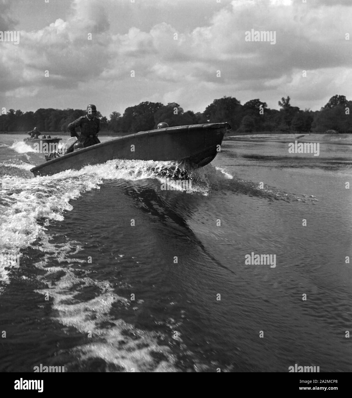 Original-Bildunterschrift: Pionier-Sturmboot in voller Fahrt bei der  Überquerung eines Stromes zur Sicherung des feindlichen Ufers, Deutschland  1940er Jahre. Storm boat crossing a river for saving the hostile shore,  Germany 1940s Stock Photo -