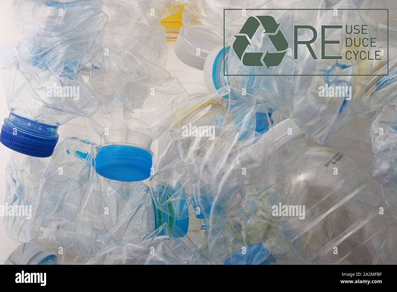 close up of crushed plastic bottles and symbol of reuse reduce recycle on the white background