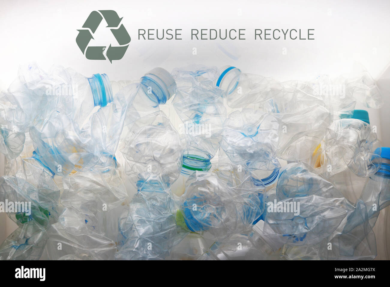 pile of crushed plastic bottles and recycle symbol put in a white