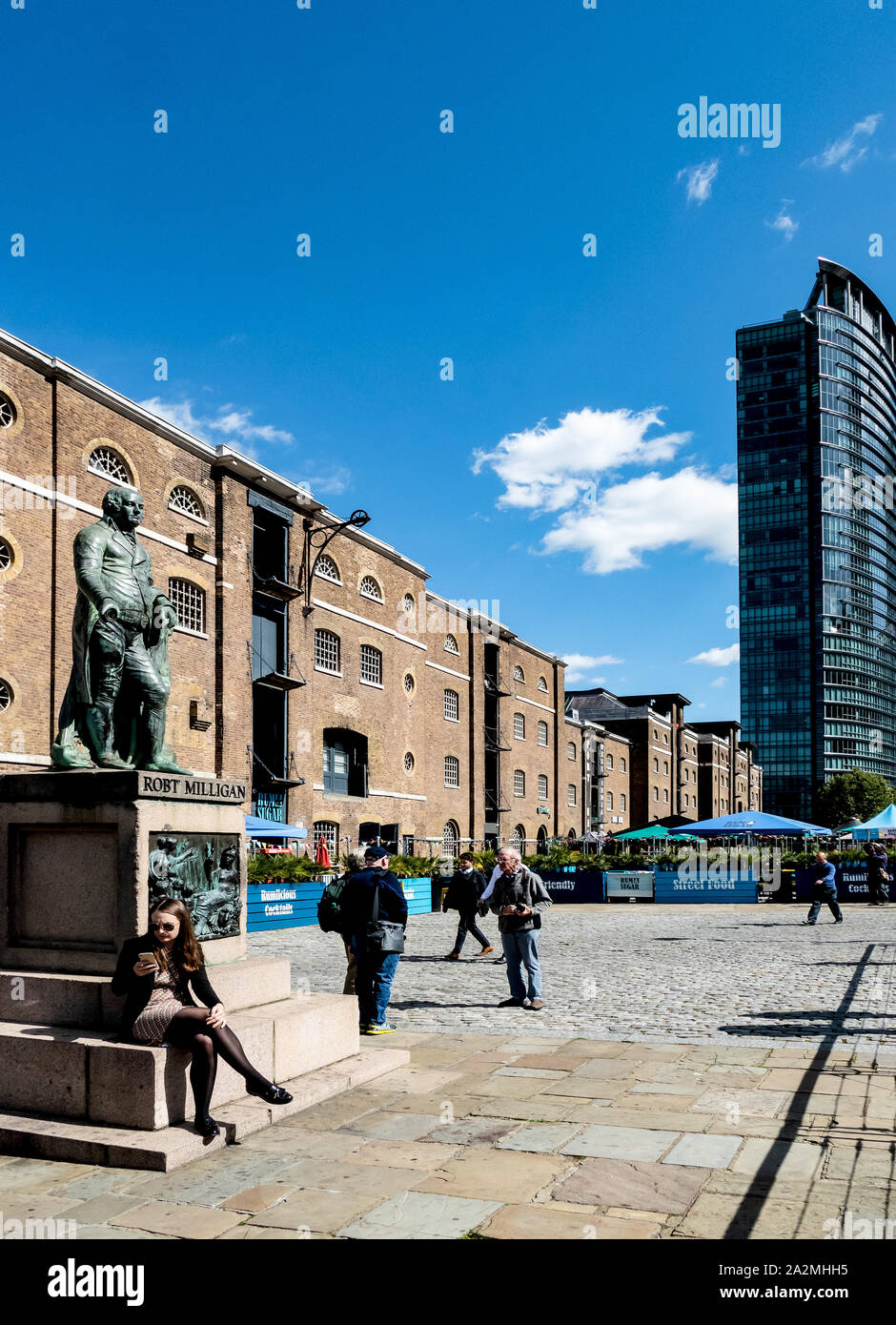The statue of Robert Milligan, the founder of West India Docks, in Canary Wharf, with  the refurbished original warehouses in background Stock Photo