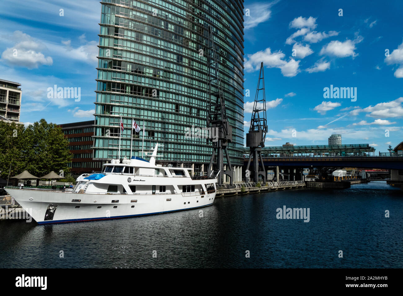 A luxury yacht moored in the waterway of Canary Wharf, London,  with the high rise business building in the background Stock Photo