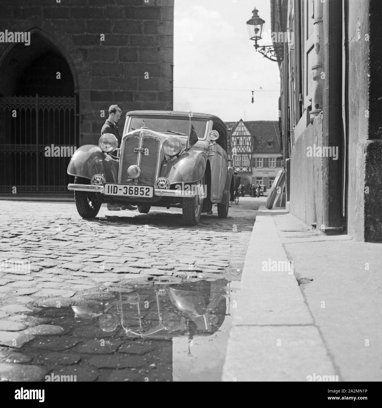 Ein Auto eines Parteifunktionärs auf dem Kopfsteinpflaster vor einem Rathaus in Deutschland, 1930er Jahre. Car of a Nazi official parking in front of a city hall in Germany, 1930s. Stock Photo